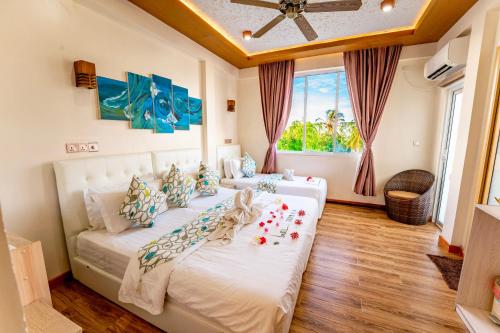 ein Schlafzimmer mit einem großen weißen Bett und einem Fenster in der Unterkunft Vilu Thari Inn Maldives in Mahibadhoo
