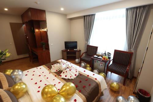a bedroom with a bed with gold balloons and a table at Gallant Hotel in Hanoi