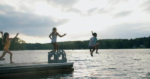 three girls jumping off a dock into a lake at Bonnie View Inn in Haliburton