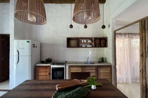 eine Küche mit einem weißen Kühlschrank und 2 Kronleuchtern in der Unterkunft Pontal da Enseada in Pôrto de Pedras