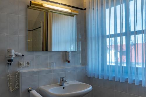 a bathroom with a sink and a mirror and a window at Servus Gelting in Geretsried