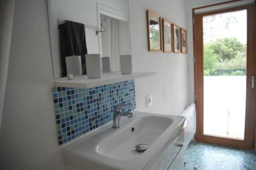 La salle de bains blanche est pourvue d'un lavabo et d'un miroir. dans l'établissement Les Hauts de Saint Siffret, à Saint-Siffret