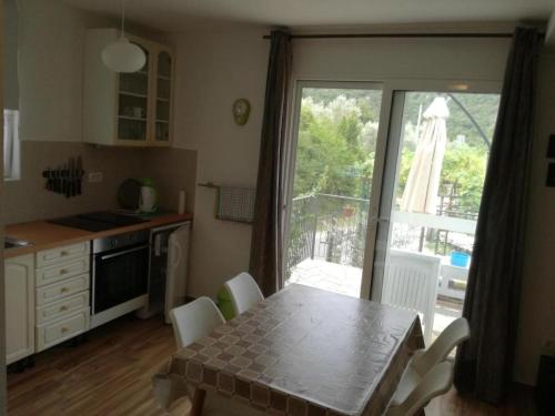 a kitchen with a table with chairs and a window at Apartmani Stanislav in Petrovac na Moru