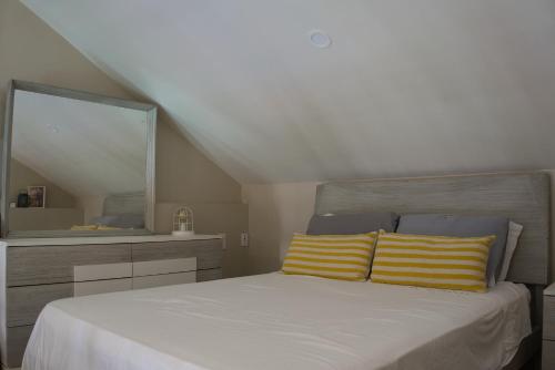 a bedroom with a bed with yellow and white pillows at City Views Spacious Mezzanine Apartments in Willemstad