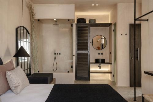a bedroom with a bed and a chair and a mirror at Emery Hotel in Naxos Chora