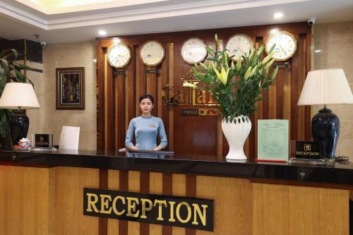a woman standing at a reception counter in a hotel lobby at Gallant Hotel in Hanoi