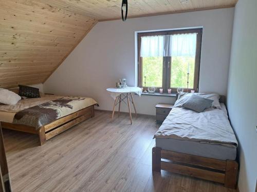 a bedroom with two beds and a table and a window at Siedlisko Magiczne Cimanie in Cimanie