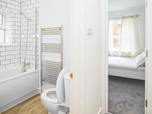 uma casa de banho branca com um WC e uma cama em Sahara Rose em East Grinstead