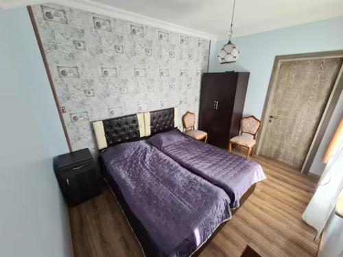 コブレチにあるGuest House Rustaveliのベッドルーム(紫色のベッド1台、椅子2脚付)