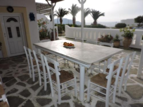 una mesa blanca y sillas con un bol de fruta. en Maria Apartments en Amoopi