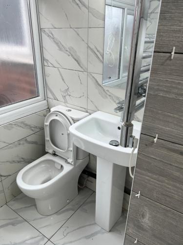 La salle de bains blanche est pourvue de toilettes et d'un lavabo. dans l'établissement Room in new flat, à Walsall