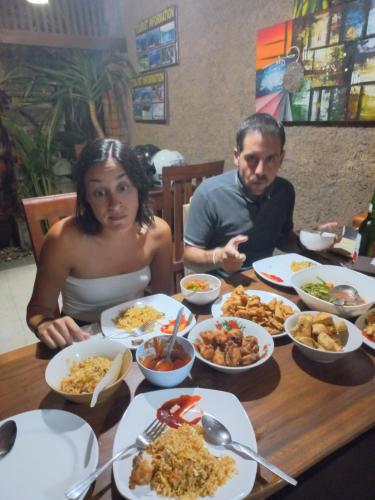 a man and a woman sitting at a table with food at Werkudara Guest House in Ubud