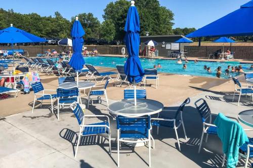 una piscina con mesas, sillas y sombrillas azules en Spring Retreat with Game Room en New Rome