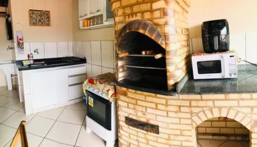 een keuken met een bakstenen oven en een magnetron bij Nossa Casa Arraial HOSTEL e SUÍTE in Arraial do Cabo