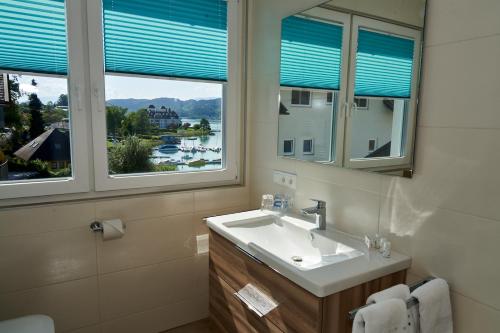 ein Badezimmer mit einem Waschbecken und zwei Fenstern in der Unterkunft Appartements am See in Maria Wörth