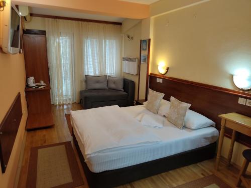 a bedroom with a large bed and a chair at Hotel Kapistec Skopje in Skopje