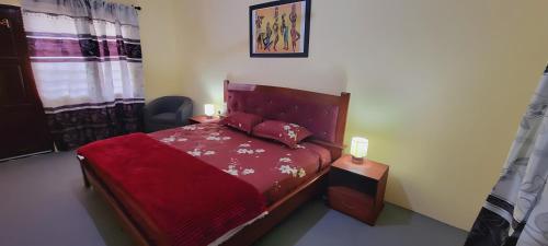 een slaapkamer met een bed met een rood dekbed bij Lord's Hands Guesthouse Hotel in Winneba