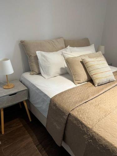 a bed with pillows and a table with a lamp at Koroni Luxury Apartment in Koroni