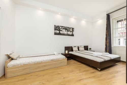ブダペストにあるReal Apartments Kertészの白い壁とウッドフロアの客室で、ベッド2台が備わります。