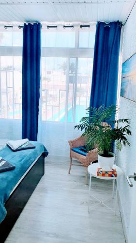 a room with blue curtains and a couch and a table at Papagayo Beach Apartments in Arona