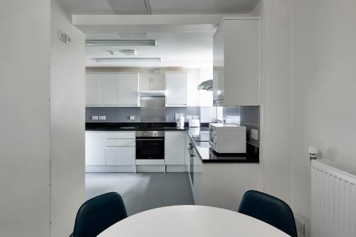 a kitchen with white cabinets and a table and chairs at Ifor Evans Hall, Camden in London