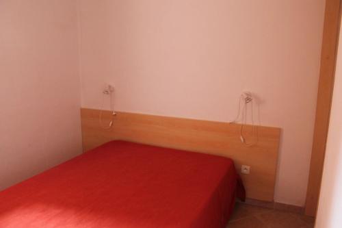 une petite chambre avec un lit avec une couverture rouge dans l'établissement Grazioso bilocale a 200 m dal mare in residence con piscina e WI-FI, à Linguizzetta