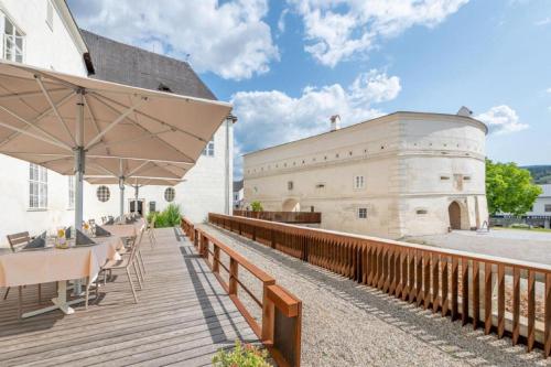 a wooden deck with tables and an umbrella next to a building at Residenz Schloss Pöggstall in Pöggstall