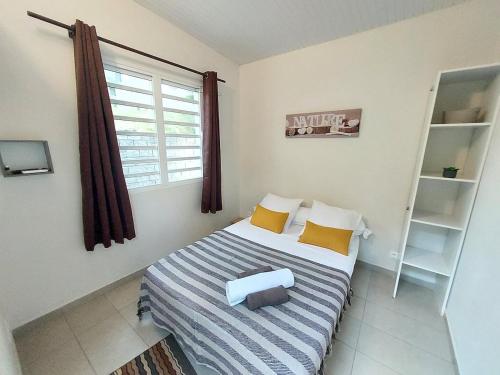 Habitación pequeña con cama y ventana en L' authentique, en La Trinité