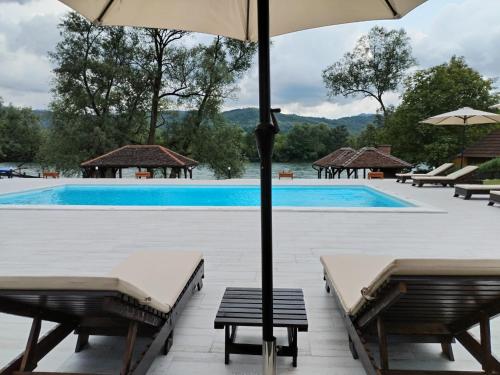 a pool with chairs and umbrellas and a swimming pool at Tri vrbe in Ljubovija