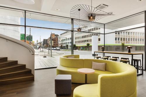 a lobby with a yellow couch and a table at Super 8 by Wyndham Koblenz in Koblenz