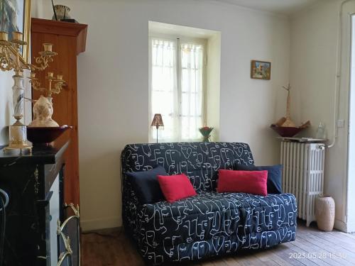 uma sala de estar com um sofá preto com duas almofadas vermelhas em VILLA ESPERANZA Suite de 2 à 4 personnes proche Zoo de Beauval et châteaux de La Loire em Valençay