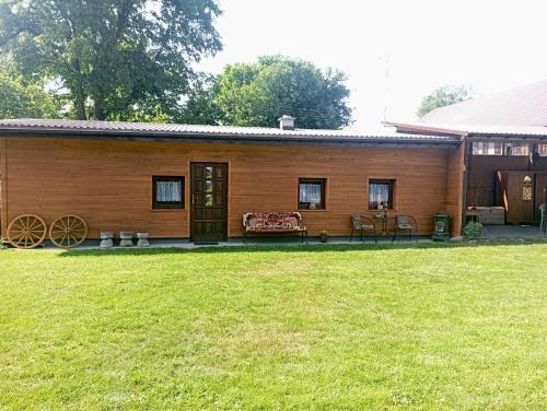 une cabane en bois avec une pelouse devant elle dans l'établissement Sołtysówka, à Wólka Nadbużna