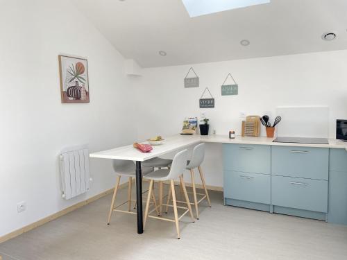 a kitchen with blue cabinets and a white table and chairs at Logement entier à la campagne proche du circuit et du zoo de la Flèche in Yvré-le-Pôlin