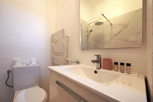 een witte badkamer met een toilet en een wastafel bij Charming Bright Studio in luxurious 16th in Parijs