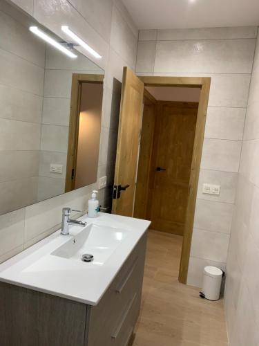 y baño con lavabo blanco y espejo. en CAL JAN - La Muralla en Bellver de Cerdanya 