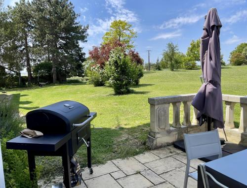 a grill and an umbrella on a patio at Le Château de Leugny in Oiron