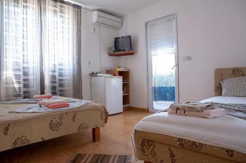 a room with two beds and a window and a refrigerator at Villa Horizon Canj in Čanj