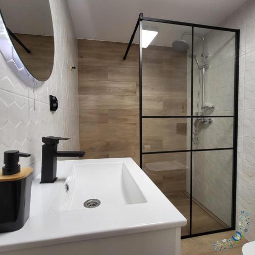 a bathroom with a sink and a glass shower at Studio 4-osobowe in Gowidlino