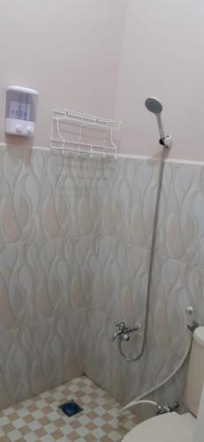 a shower in a bathroom with a toilet and a wall at Homestay ZRMA Palu in Palu
