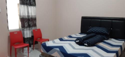 a bedroom with a bed and two red chairs at Homestay ZRMA Palu in Palu
