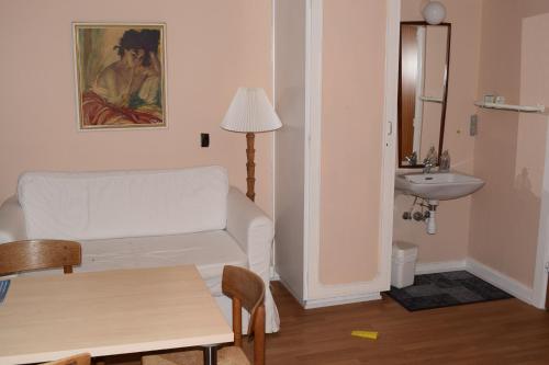 a living room with a white couch and a sink at Nygammelsø Bed & Breakfast in Stege