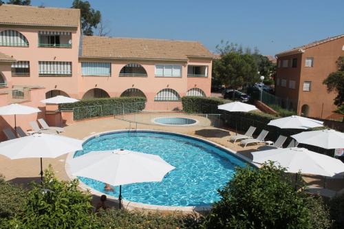 une piscine avec des parasols et des chaises et un bâtiment dans l'établissement Grazioso bilocale a 200 m dal mare in residence con piscina e WI-FI, à Linguizzetta