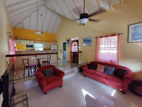 a living room with two red couches and a kitchen at BenCastle Villa in Gros Islet