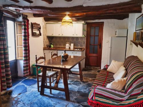- une cuisine avec une table et un canapé dans une chambre dans l'établissement La Casa de la Bombilla Verde, à Trevélez