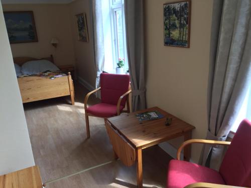 a living room with two chairs and a table and a bed at Nygammelsø Bed & Breakfast in Stege