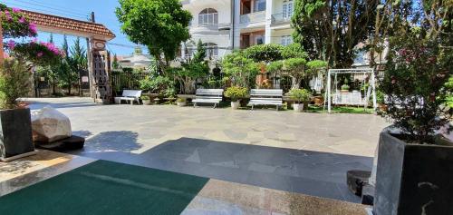 a patio with benches and trees and a building at Villa Pink House in Da Lat