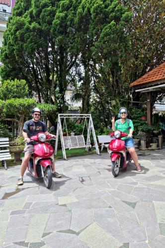two people riding on scooters in a park at Villa Pink House in Da Lat