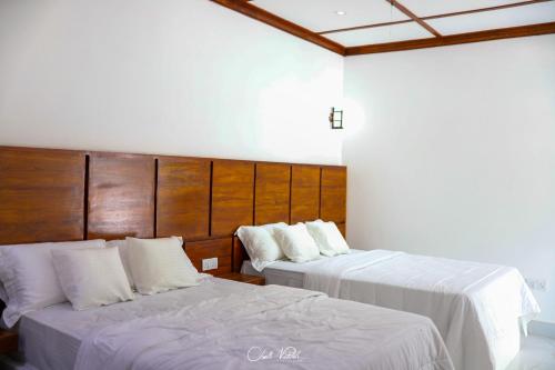 two beds in a hotel room with white sheets at Ceylonta Beach Resort in Hambantota