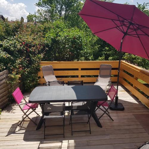 une table, des chaises et un parasol sur une terrasse dans l'établissement Appartement entre lac et montagnes, à Saint-Paul-en-Chablais
