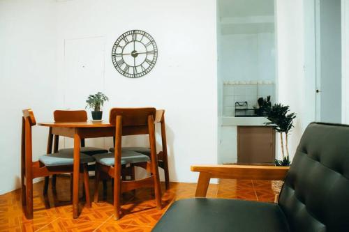 une salle à manger avec une table, des chaises et une horloge dans l'établissement Relaxing & Accessible Apartment, à Matinkanana
